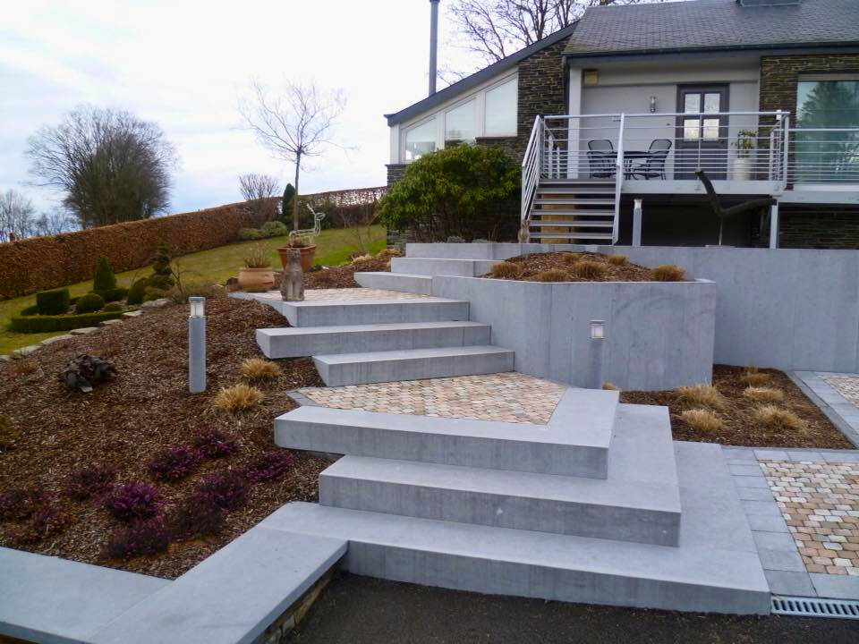 Escalier en pierre grise et pavés dans un jardin en pente